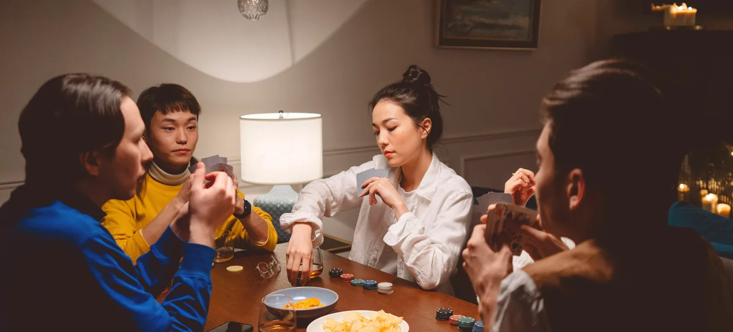 A relaxed group of friends playing a casual home poker game around a wooden table